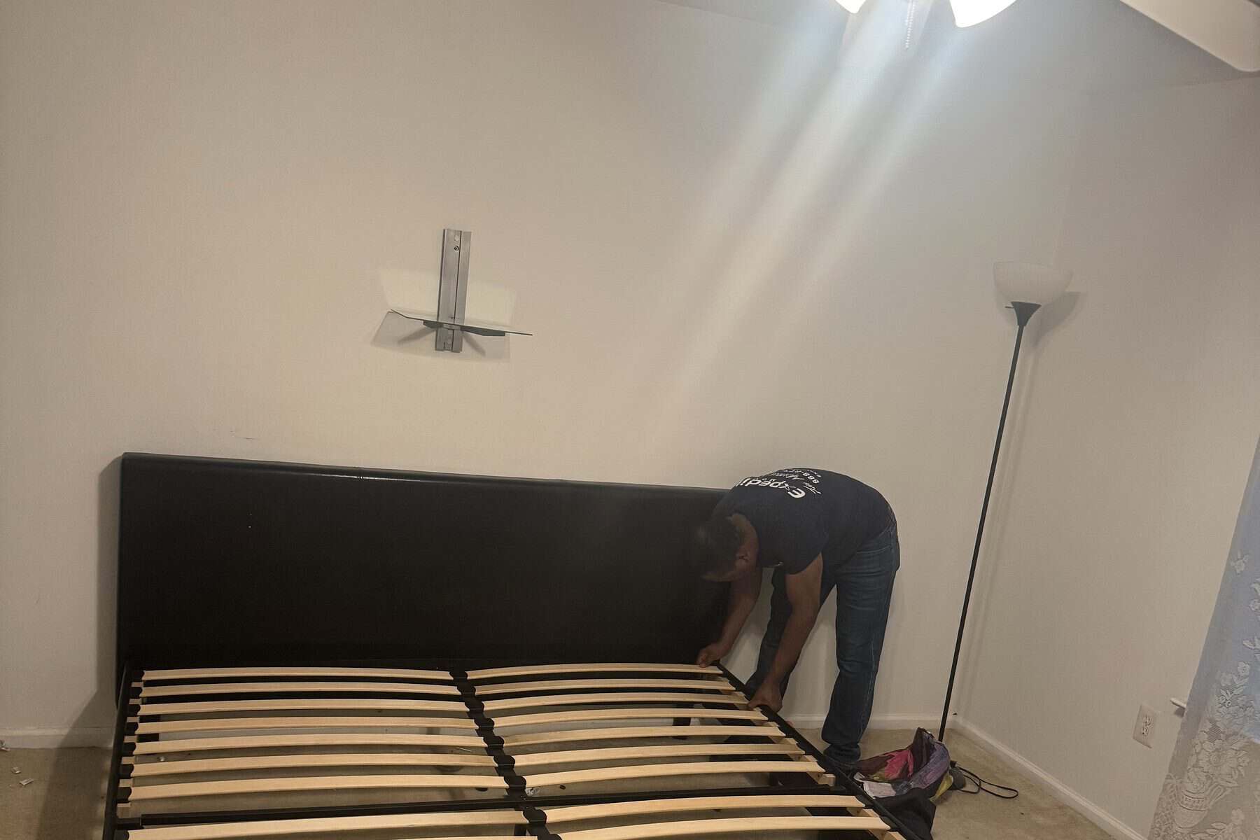 Expedite Moving crew member reassembling a bed frame in a customer's new home