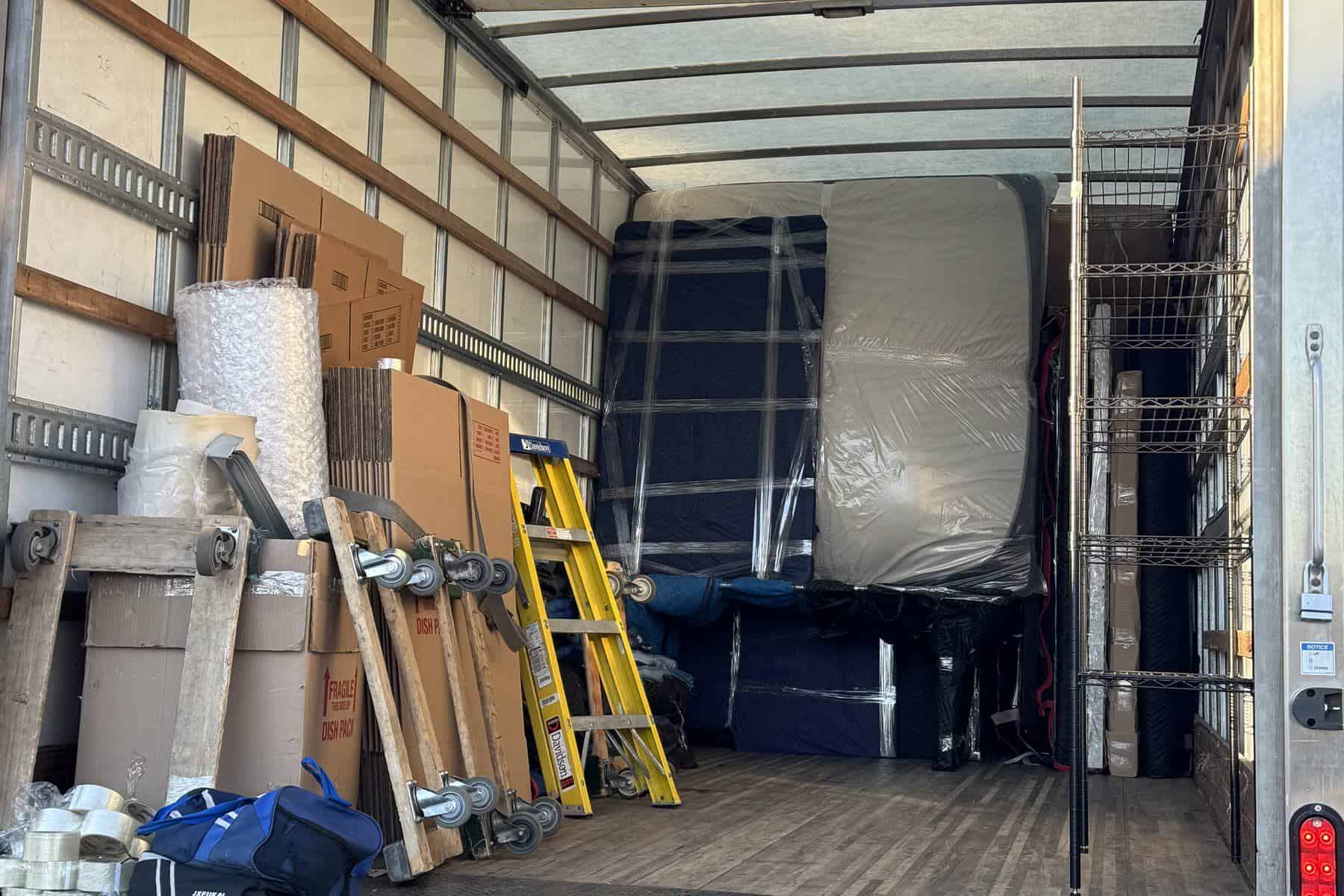 An Expedite Moving truck loaded floor to ceiling with wrapped furniture, boxes and a mattress