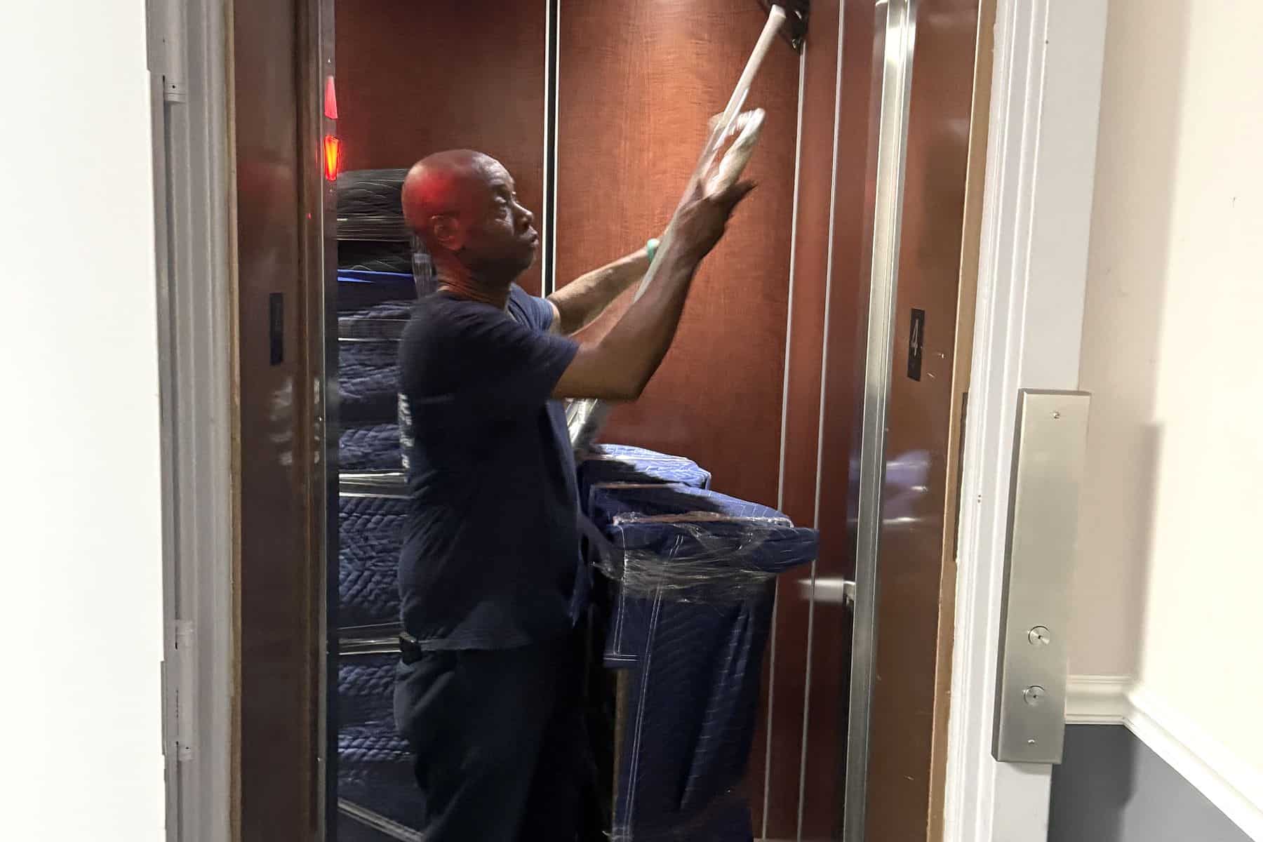 An Expedite Moving crew member operating a freight elevator during an apartment move
